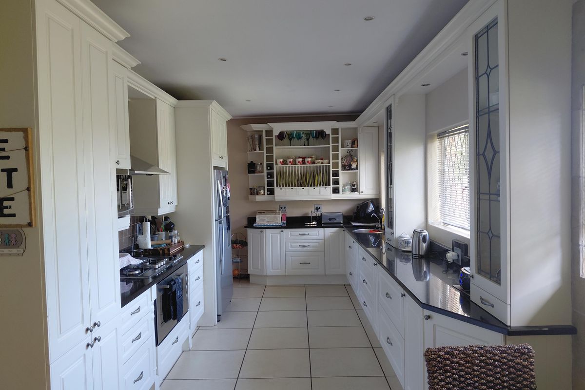 A well-appointed kitchen featuring classic white cabinetry, dark granite countertops, integrated appliances, and ample storage space with a functional layout.