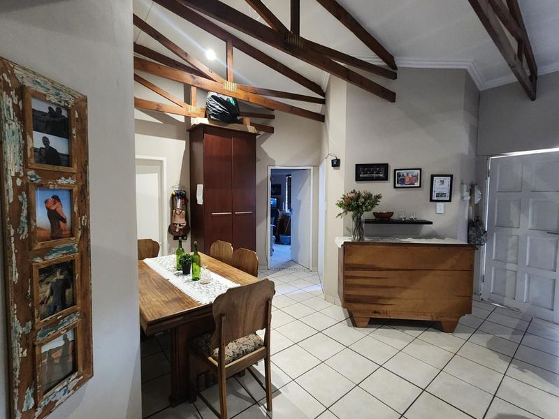 Open plan dining area featuring exposed timber roof trusses, tiled flooring, and direct access to adjacent rooms.