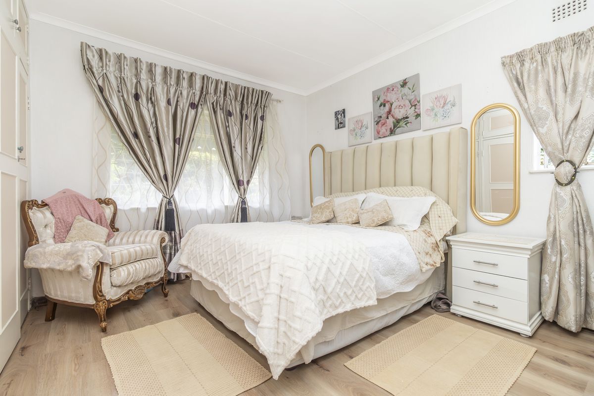 A well-maintained bedroom featuring light-toned laminate flooring, coved ceilings, and a built-in cupboard, offering a bright and comfortable living space.