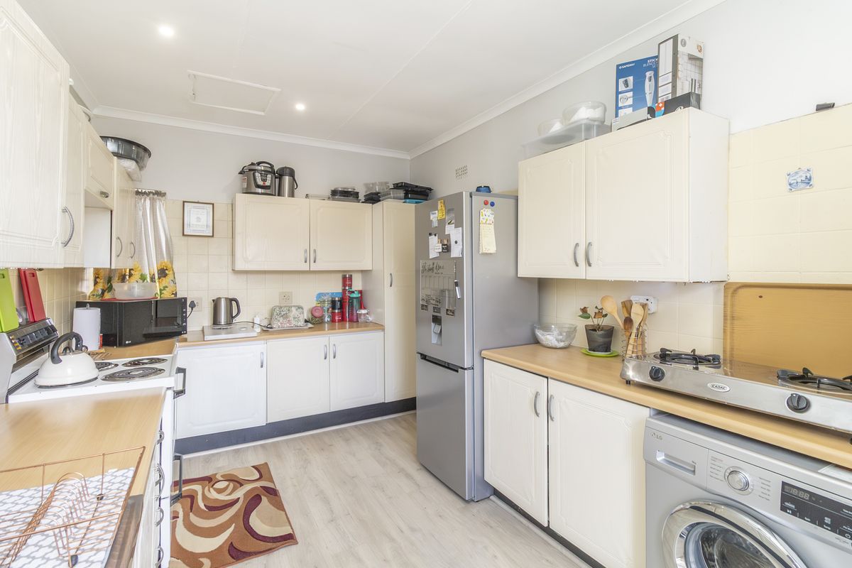 A functional kitchen featuring white cabinetry, laminate countertops, tiled backsplash, and dedicated space for laundry appliances.
