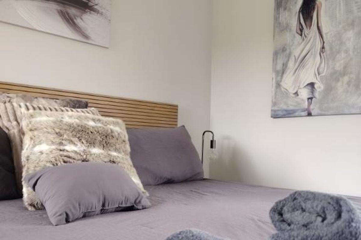 A modern bedroom featuring a contemporary slatted timber headboard and neutral wall finishes.
