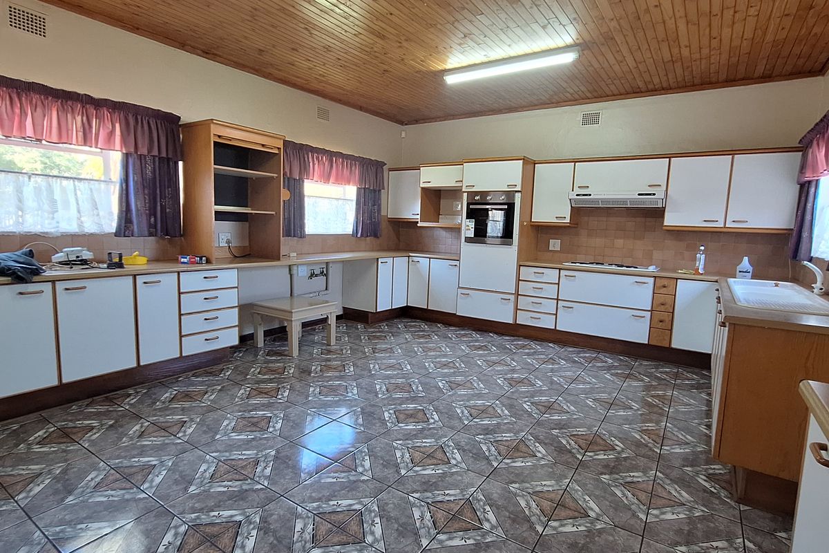 Spacious kitchen featuring extensive built-in cabinetry, integrated oven, extractor fan, and tiled flooring, offering a functional layout with ample storage and workspace.