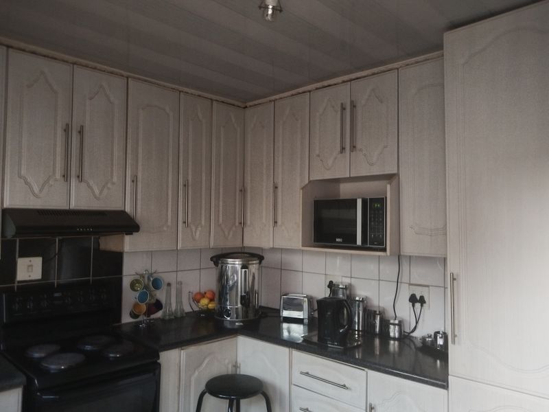 A functional kitchen featuring traditional cabinetry, tiled backsplash, and integrated appliance housing, offering a practical layout with potential for modern cosmetic updates.