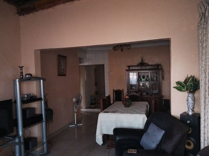Open plan living and dining area featuring tiled flooring and a transition space, requiring cosmetic updates to the ceiling and wall finishes.
