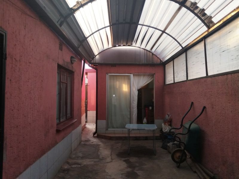 A covered outdoor patio area featuring a translucent arched roof, concrete flooring, and direct access to the interior via a sliding glass door.