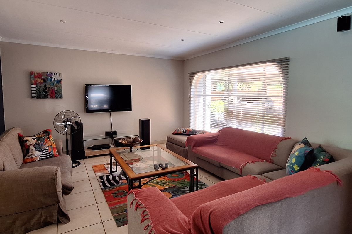 A comfortable living room featuring tiled flooring, recessed ceiling lighting, and large windows with fitted blinds, providing a functional and inviting space.