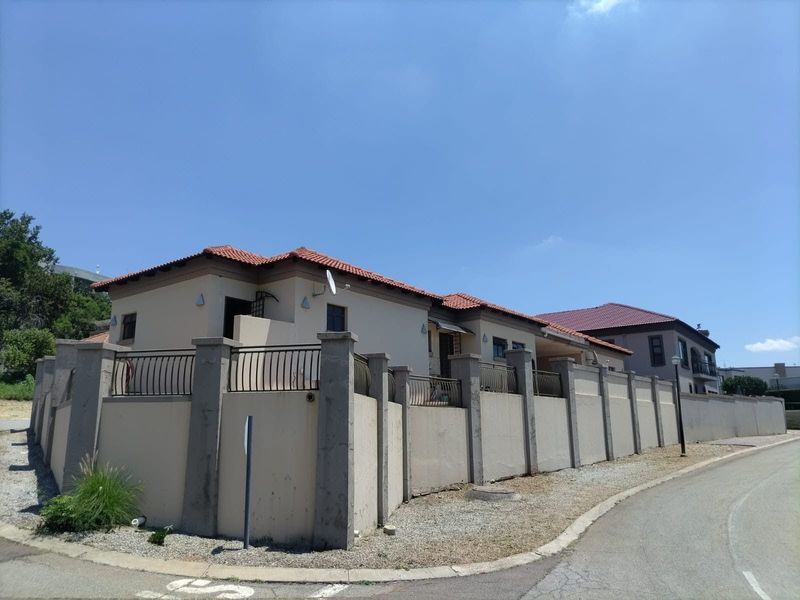 A view of the property's exterior facade featuring a perimeter wall with metal fencing and a tiled roof structure.