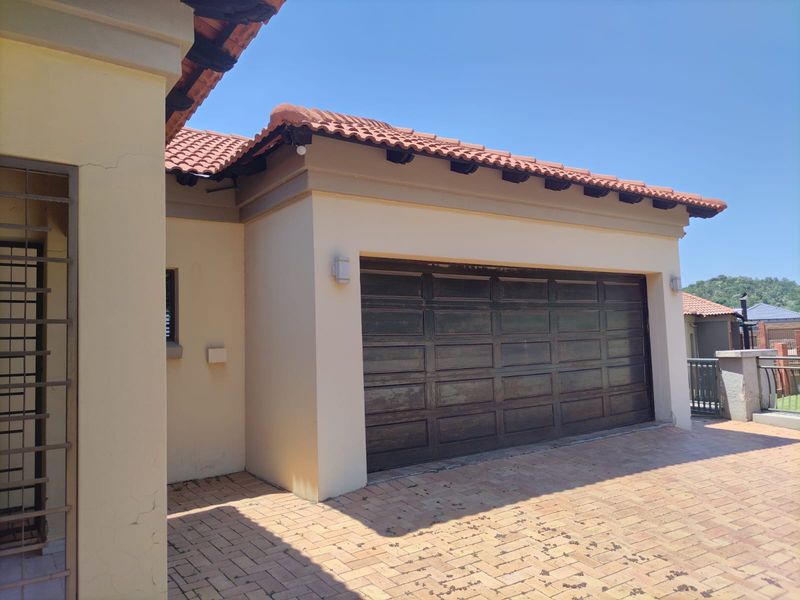 Exterior view of a residential garage featuring a sectional door, tiled roof, and paved driveway area.