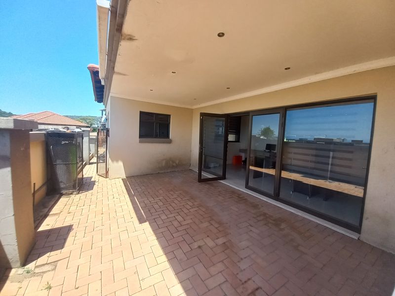 A paved outdoor patio area featuring recessed lighting and large sliding glass doors providing access to the interior living space.