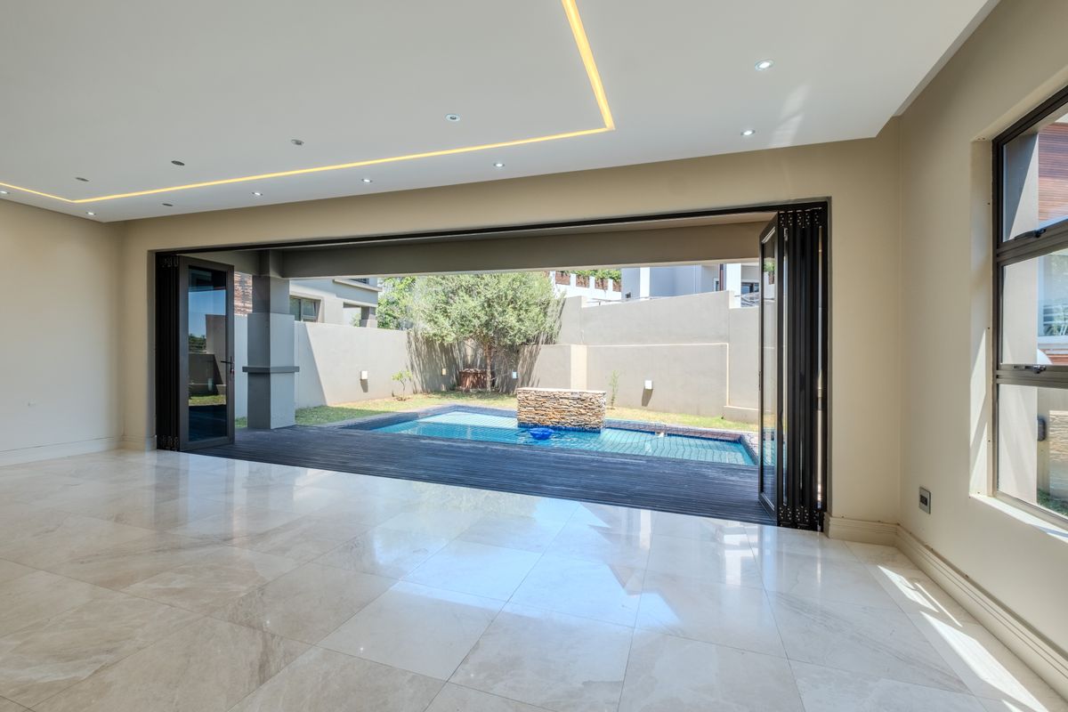 Spacious living area featuring large stackable glass doors that open onto a private deck and swimming pool area.