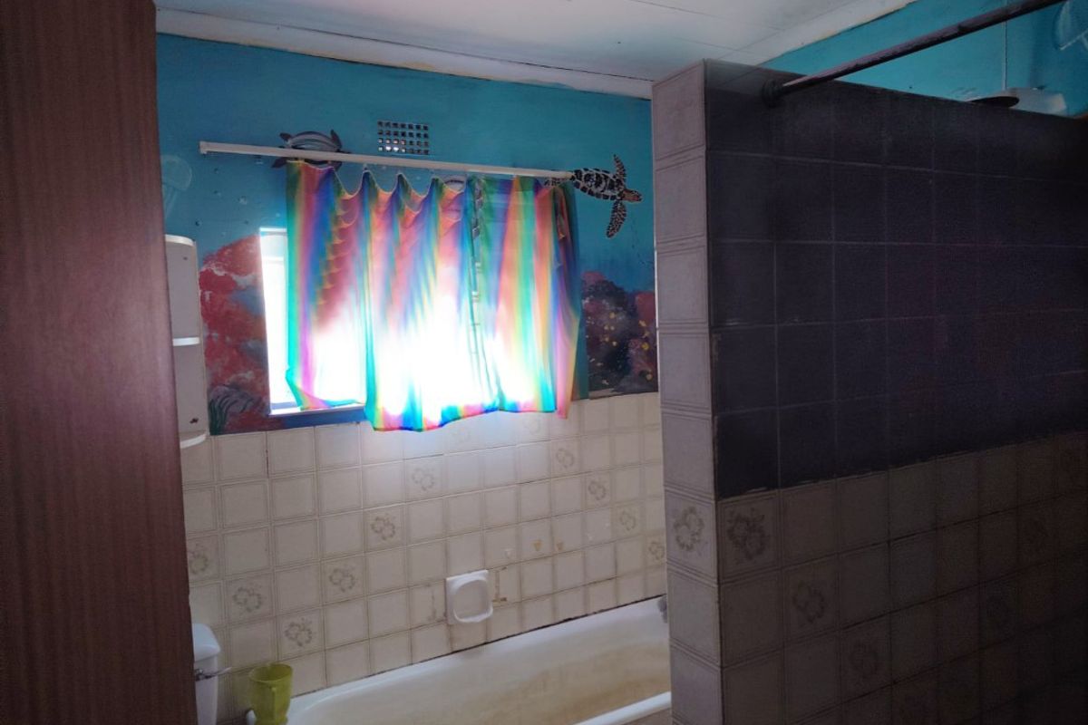 A dated bathroom featuring a bathtub and tiled walls, requiring cosmetic updates and modernization to improve its overall condition and appeal.