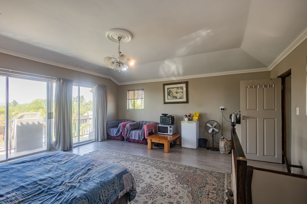 Spacious bedroom featuring laminate flooring, coved cornicing, a decorative ceiling rose, and large sliding glass doors providing access to an outdoor balcony.