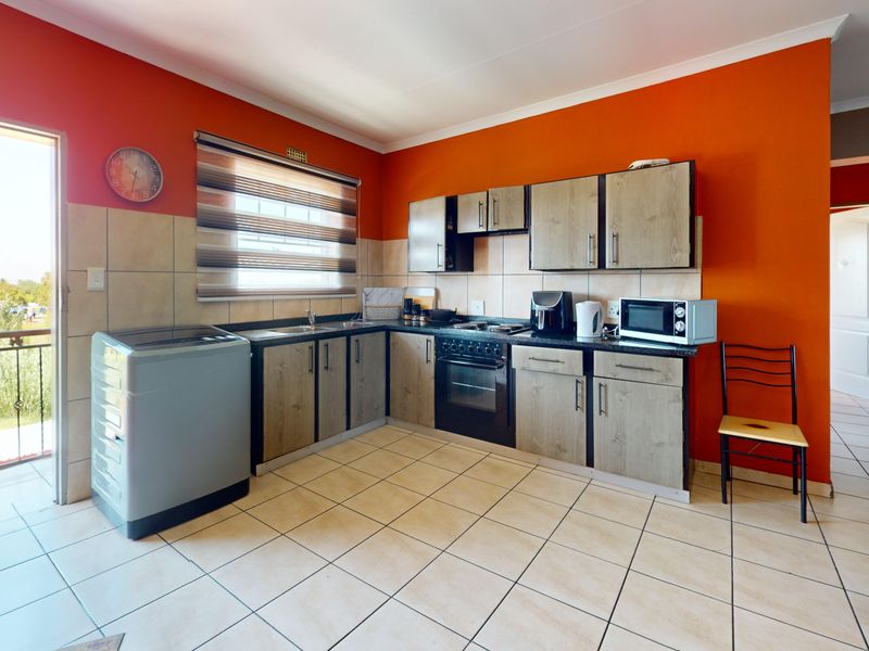 Functional kitchen featuring wood-look cabinetry, tiled backsplash, built-in oven and hob, with direct access to an outdoor balcony area.