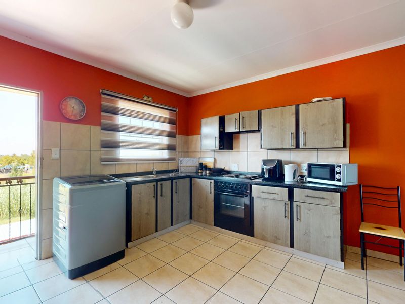 A functional kitchen featuring built-in cabinetry, laminate countertops, a built-in oven, and tiled flooring, with direct access to an outdoor balcony area.