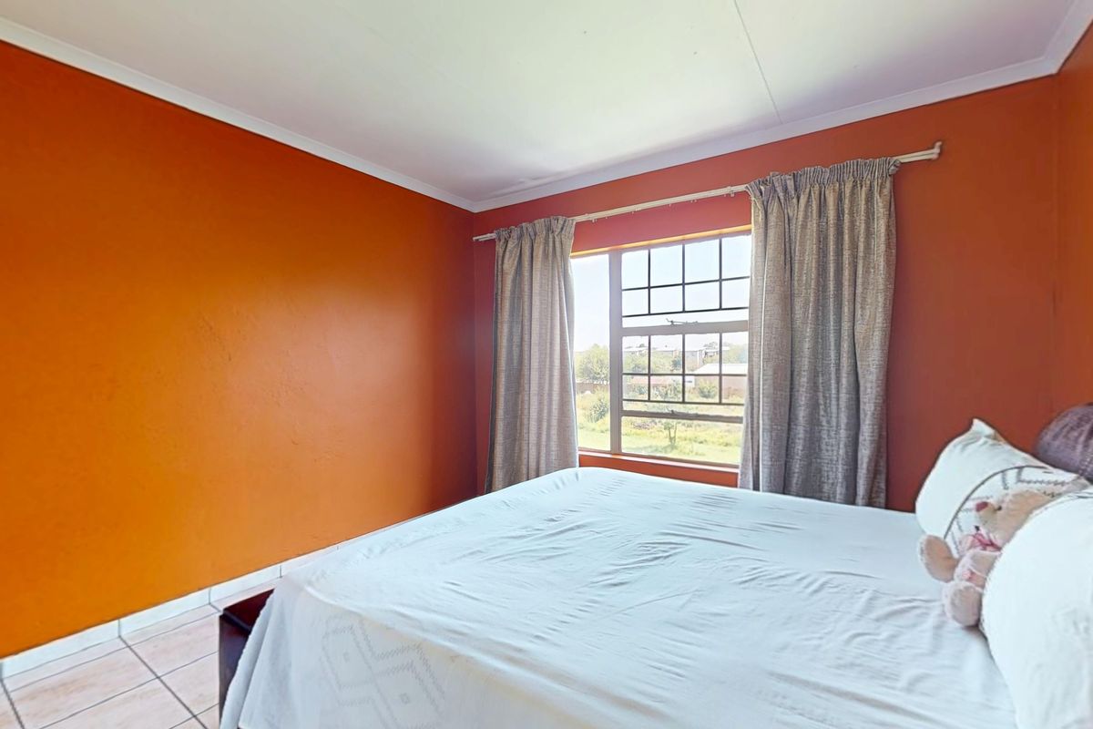A bedroom featuring tiled flooring, a grid-pattern window, and coved ceiling details, providing a functional space with potential for modern updates.