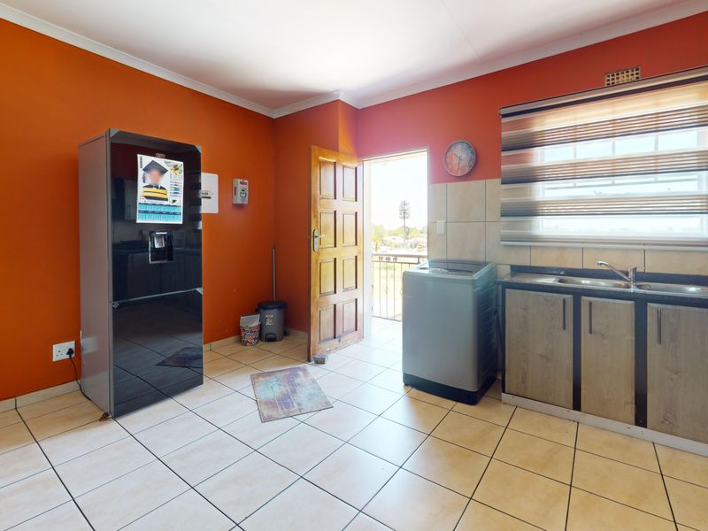A functional kitchen area featuring tiled flooring, built-in cabinetry with a double sink, and direct access to an exterior balcony.