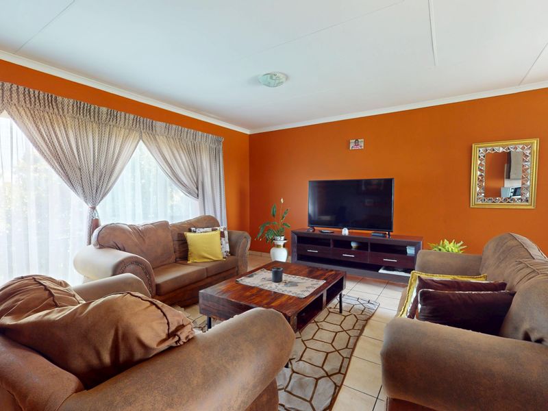 A spacious living room featuring tiled flooring and a large sliding glass door that provides ample natural light.