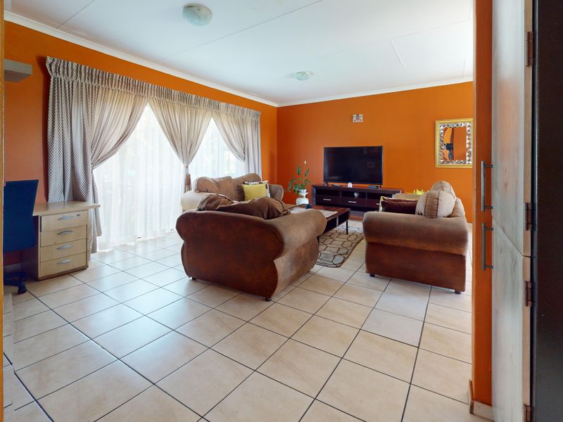 Spacious living room featuring neutral tiled flooring and a large sliding glass door that provides ample natural light.