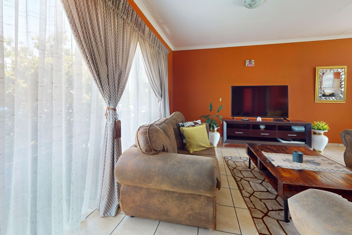 A living room featuring tiled flooring and a large sliding glass door that provides natural light.