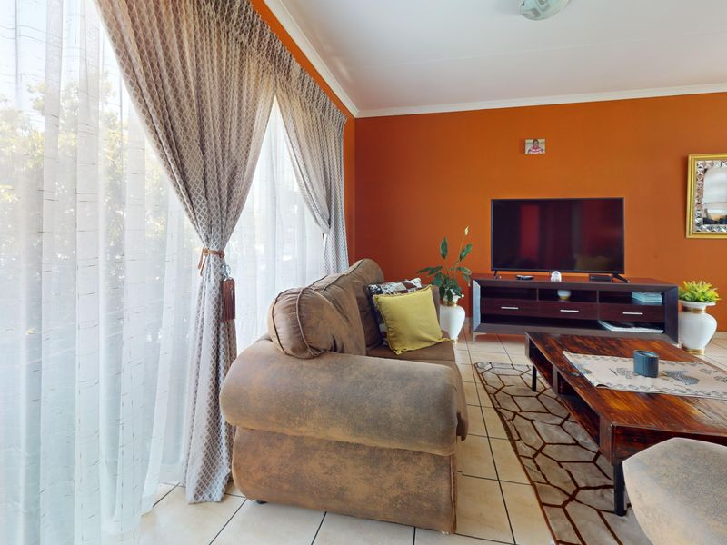 A living room featuring tiled flooring and a large sliding glass door that provides natural light.