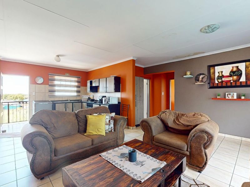 Open-plan living area featuring tiled floors and an integrated kitchen with built-in cabinetry, leading directly to an outdoor balcony.