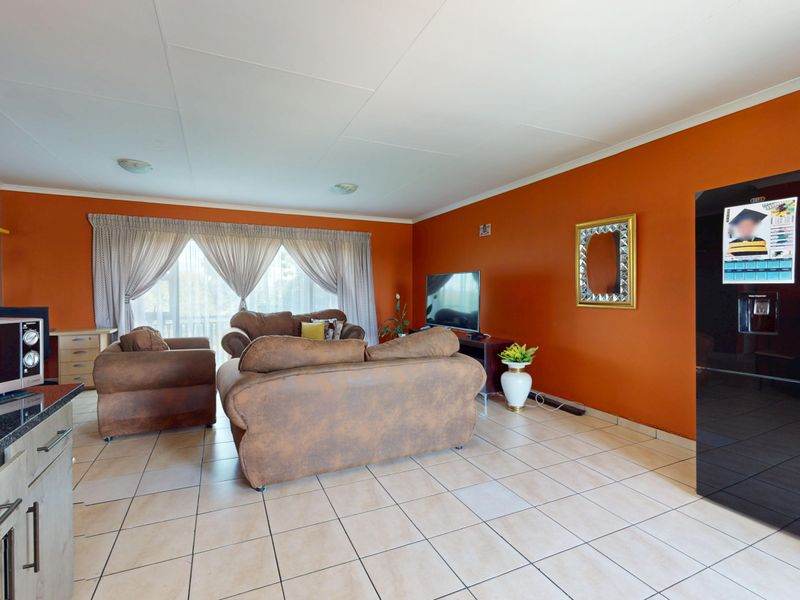 Open plan living area featuring tiled flooring, integrated kitchen cabinetry with granite countertops, and access to a balcony through sliding glass doors.