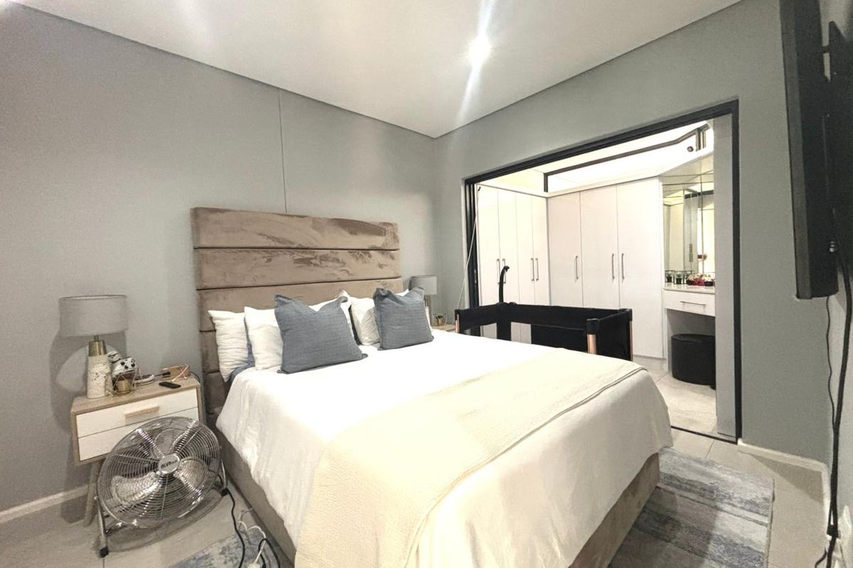 Spacious bedroom featuring tiled flooring and an adjoining dressing area with built-in cupboards and a vanity station.