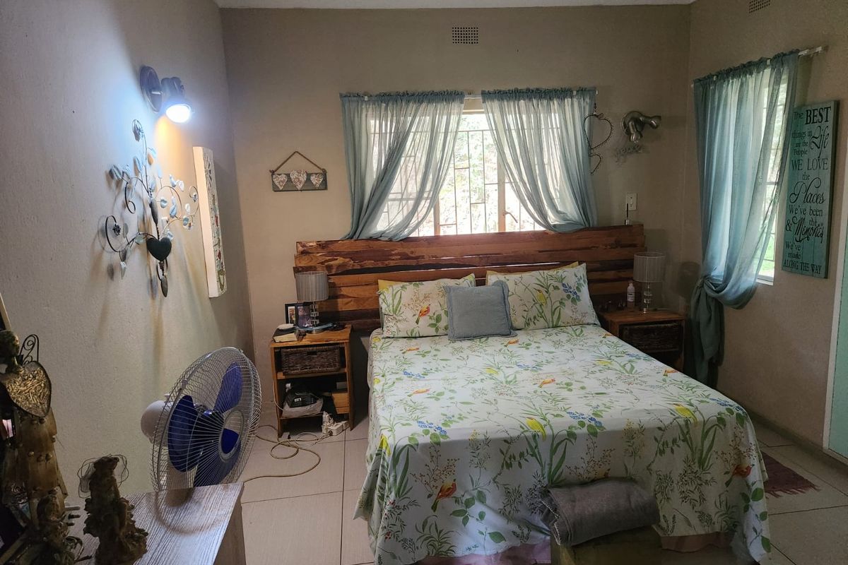 A functional bedroom featuring tiled flooring, burglar bars on the windows, and a wall-mounted light fixture.