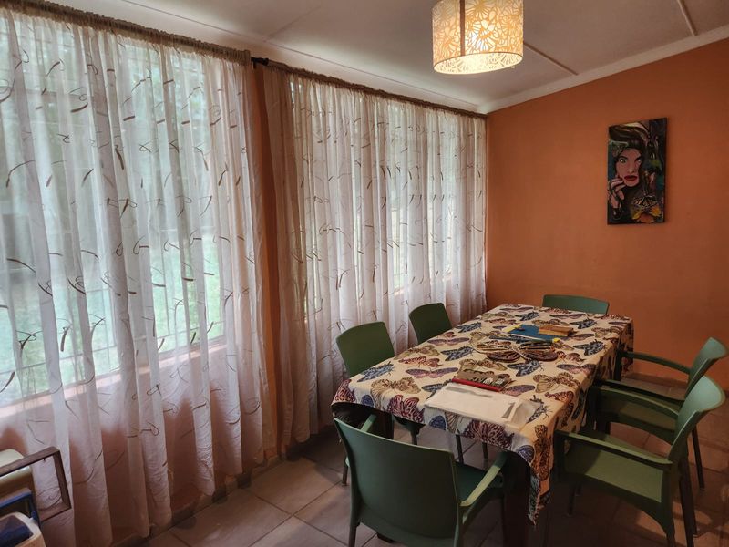 A dining room featuring tiled flooring and large windows with curtains, providing a functional space for meals.
