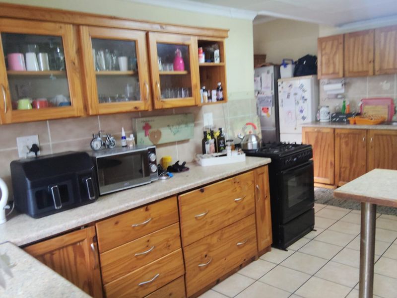 A functional kitchen featuring wooden cabinetry, tiled backsplash, and tiled flooring, offering a traditional layout with ample storage and workspace.