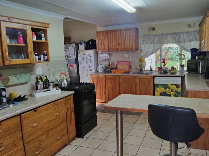 A functional kitchen featuring wooden cabinetry, laminate countertops, tiled flooring, and a freestanding oven, offering a traditional layout with ample storage space.