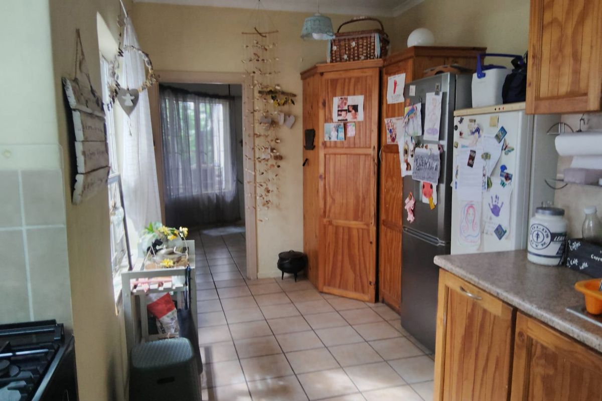 A functional kitchen featuring built-in wooden cabinetry, tiled flooring, and a gas hob, offering a practical layout with direct access to adjacent living areas.