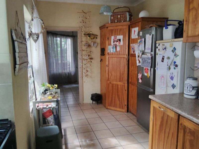 A functional kitchen featuring built-in wooden cabinetry, tiled flooring, and a gas hob, offering a practical layout with direct access to adjacent living areas.