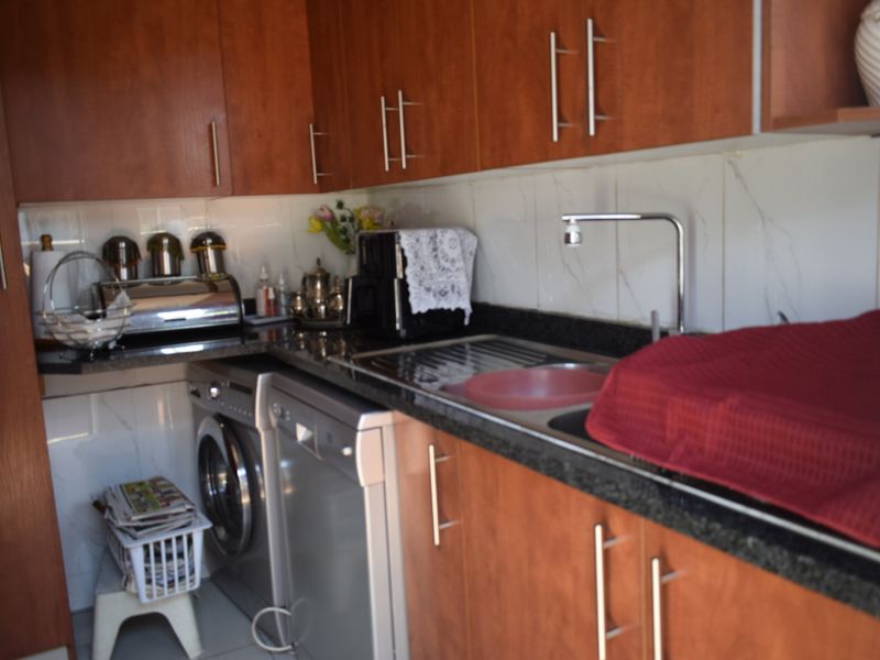 A functional kitchen featuring laminate cabinetry, granite countertops, a stainless steel sink, and integrated plumbing connections for laundry and dishwashing appliances.