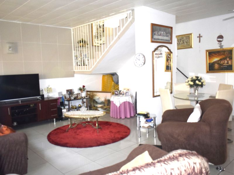 Open plan living and dining area featuring tiled flooring and an internal staircase with a white railing.