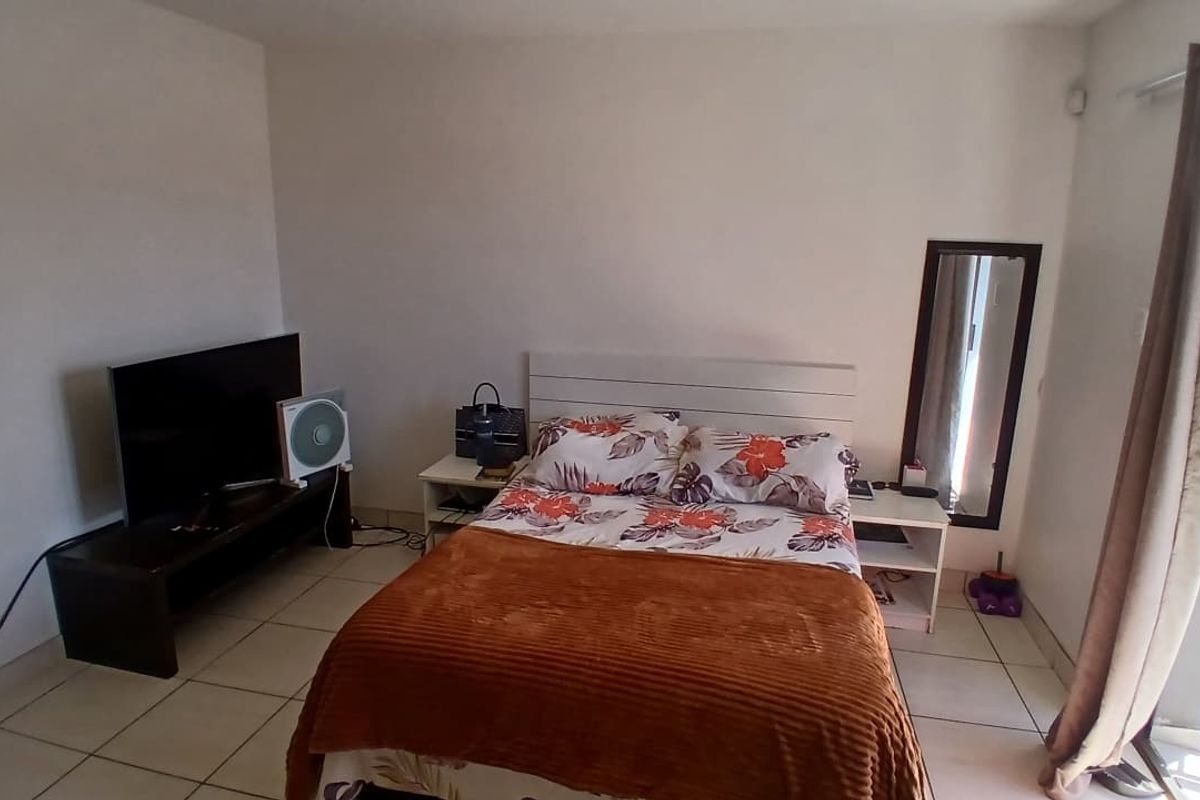 A functional bedroom featuring tiled flooring and a sliding glass door providing access to an outdoor area.