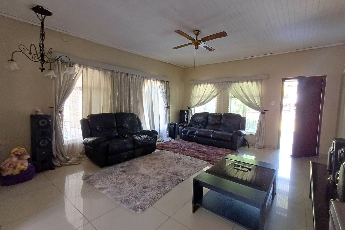 Spacious living room featuring tiled flooring, a tongue and groove ceiling, a ceiling fan, and a decorative wrought iron chandelier.