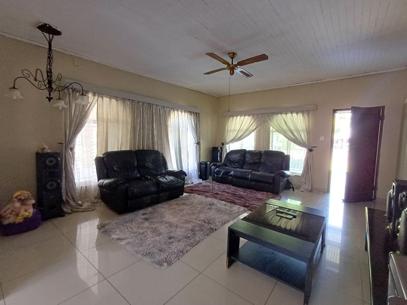 Spacious living room featuring tiled flooring, a tongue and groove ceiling, a ceiling fan, and a decorative wrought iron chandelier.