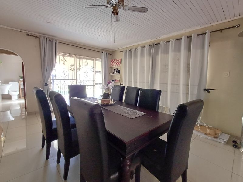 Dining room featuring tiled flooring, a ceiling fan, and sliding glass doors with security gates, providing access to the exterior.