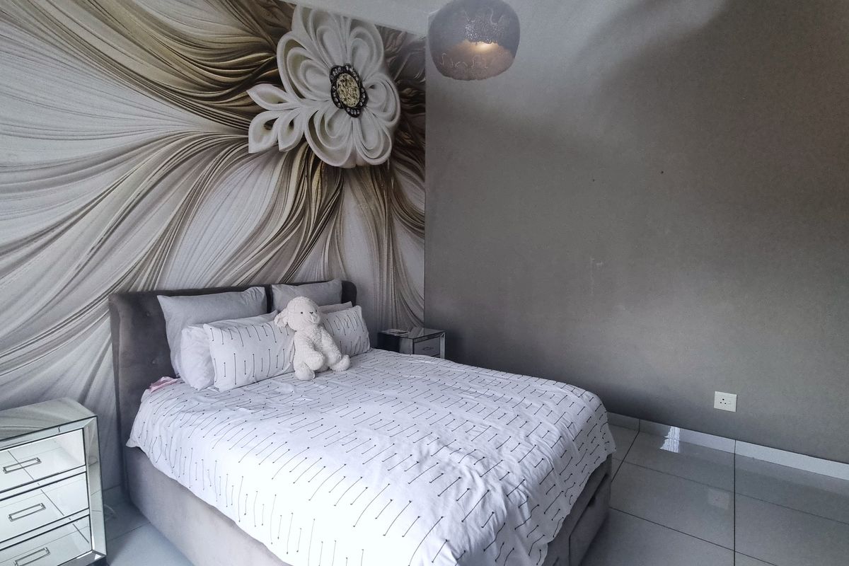 A bedroom featuring tiled flooring and a decorative feature wall.