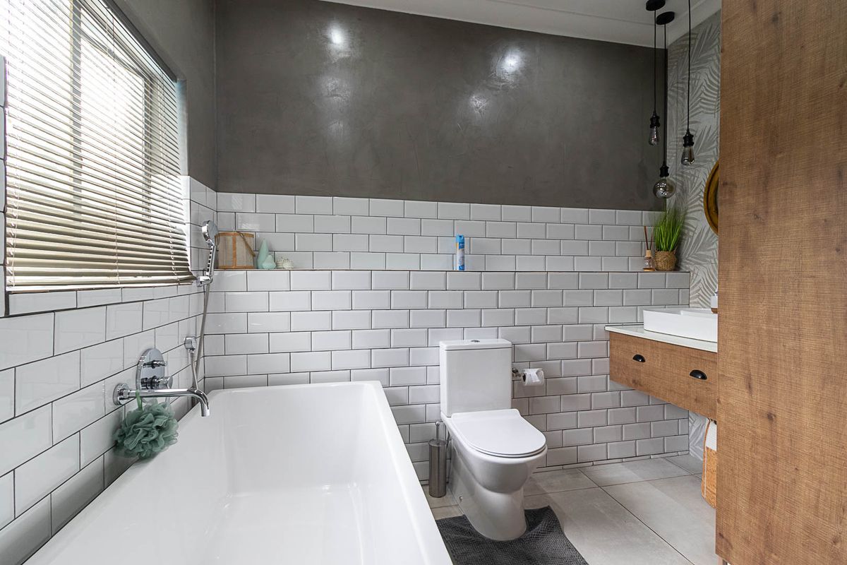 Modern bathroom featuring a freestanding bathtub, floating vanity with vessel sink, subway tile backsplash, and contemporary pendant lighting.