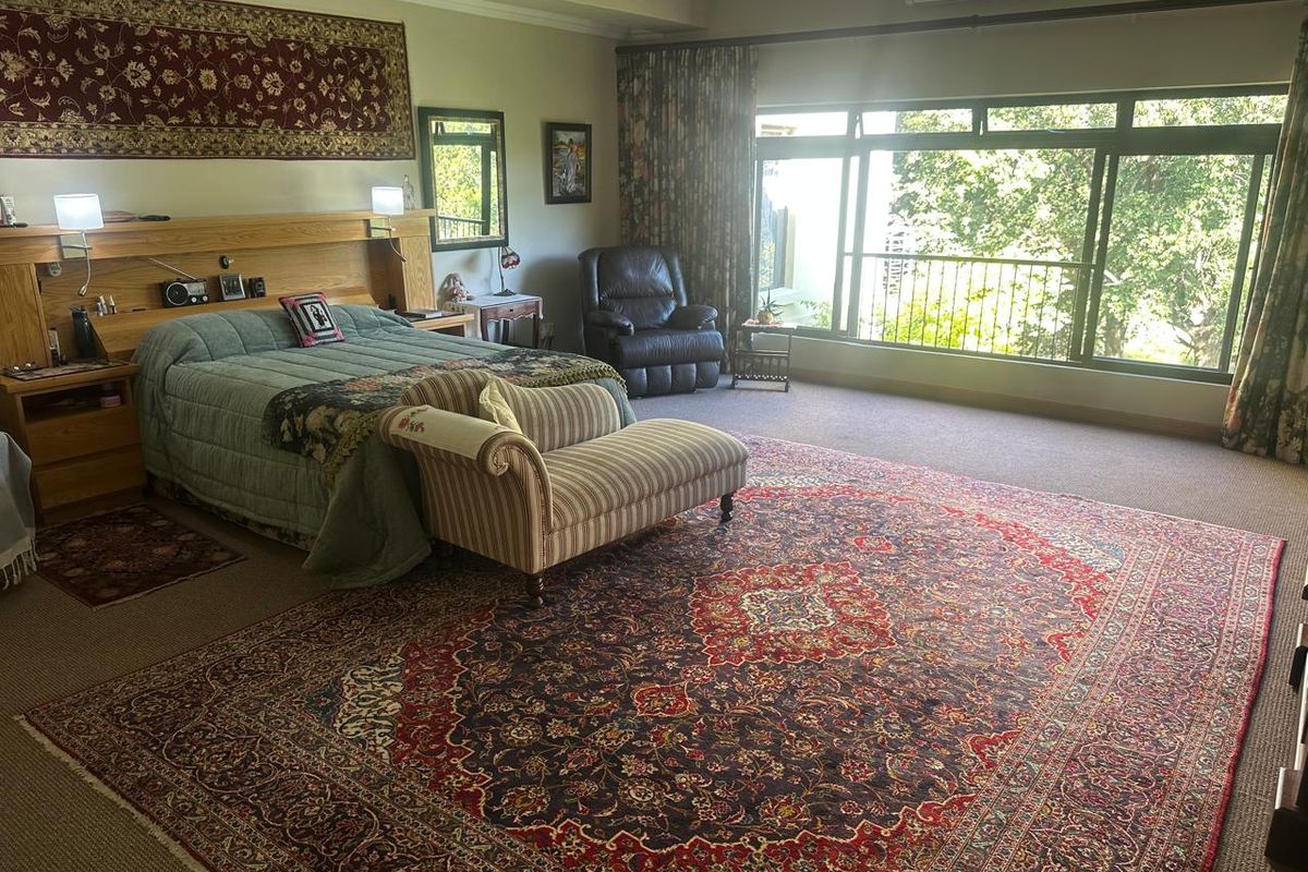 Spacious bedroom featuring a built-in headboard, wall-mounted air conditioning, and large sliding glass doors opening to a balcony with garden views.