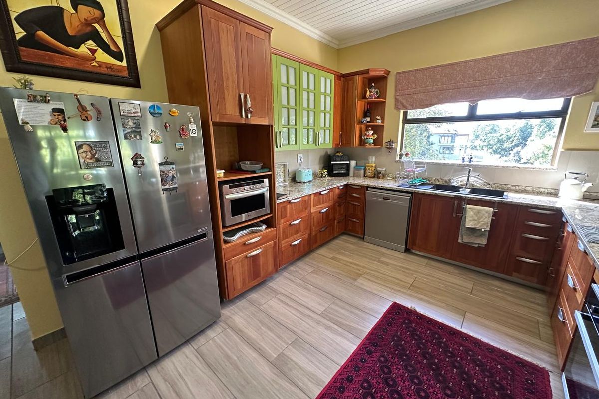 A functional kitchen featuring wooden cabinetry, granite countertops, a double basin sink, and built-in appliances, finished with tiled flooring and a tongue and groove ceiling.
