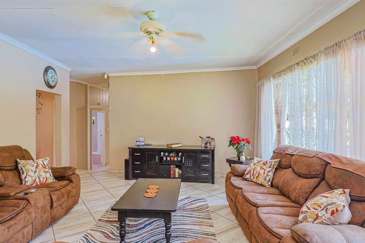 Spacious living room featuring tiled flooring, a ceiling fan, and neutral wall tones, offering a comfortable and functional layout for relaxation.