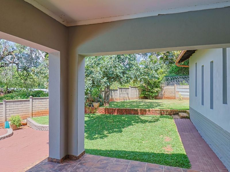 A covered patio area overlooking a private garden with brick retaining walls and paved pathways.