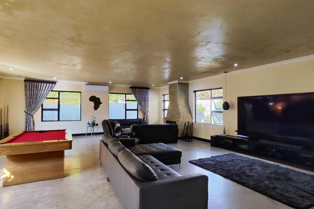 Spacious living room featuring polished concrete floors, a stone-clad fireplace, recessed lighting, and large windows with access to the outdoor area.