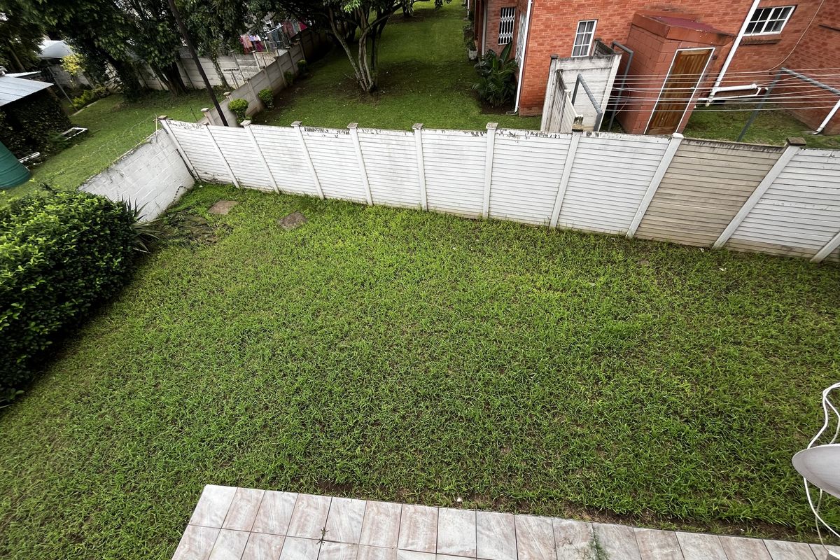 A private rear garden featuring a lawn area, tiled patio, and perimeter boundary walling.