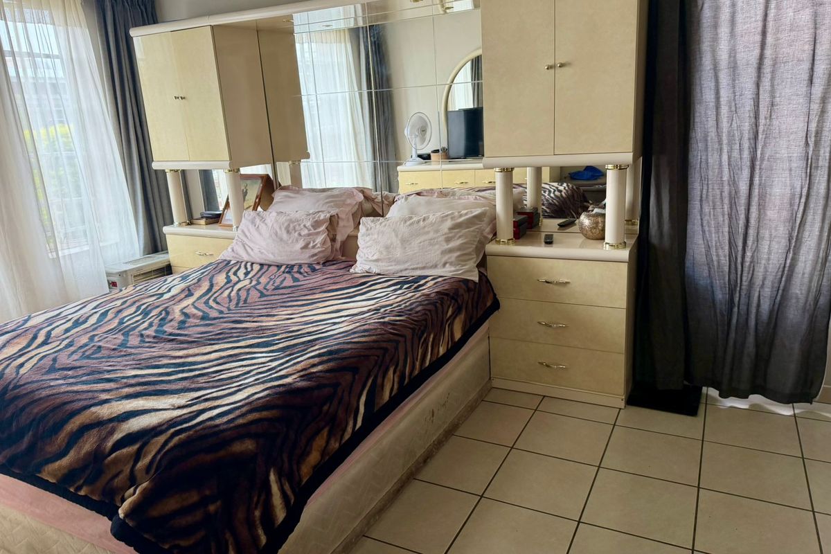 A bedroom featuring built-in cabinetry with an integrated mirrored headboard and tiled flooring.