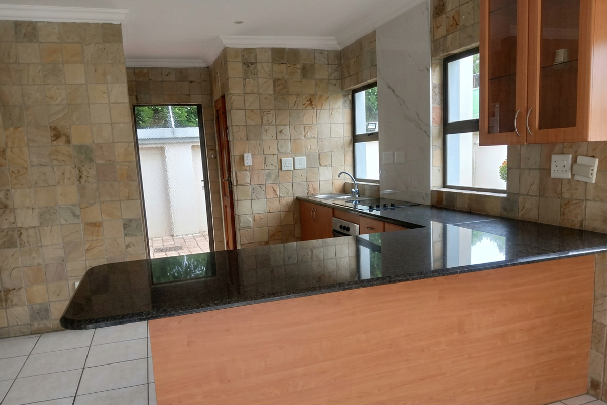 A functional kitchen featuring granite countertops, built-in cabinetry, a breakfast nook, and distinctive stone wall cladding, offering a practical layout for daily use.