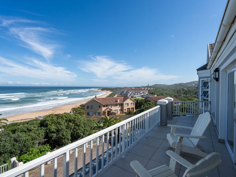 Spacious balcony featuring tiled flooring and a white balustrade, offering panoramic views of the coastline and surrounding landscape.